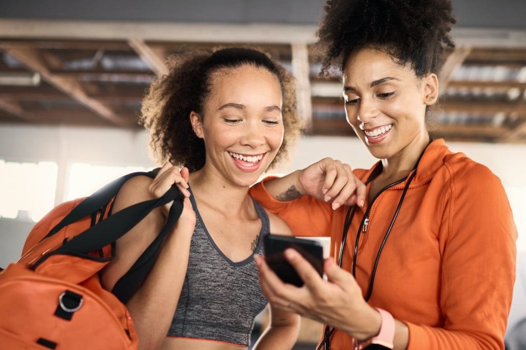 Phone, fitness and friends or athlete checking his social media after a workout or exercise at the