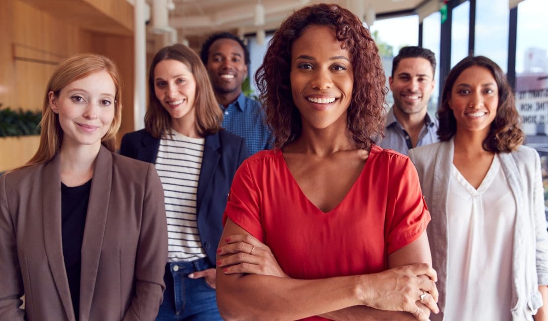 Portrait Of Multi-Cultural Business Team Standing In Modern Open Plan Office Together