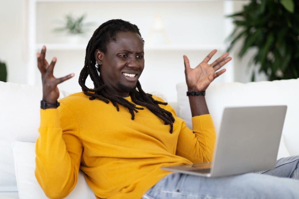 Stressed African American Guy Suffering Problems With Laptop At Home,