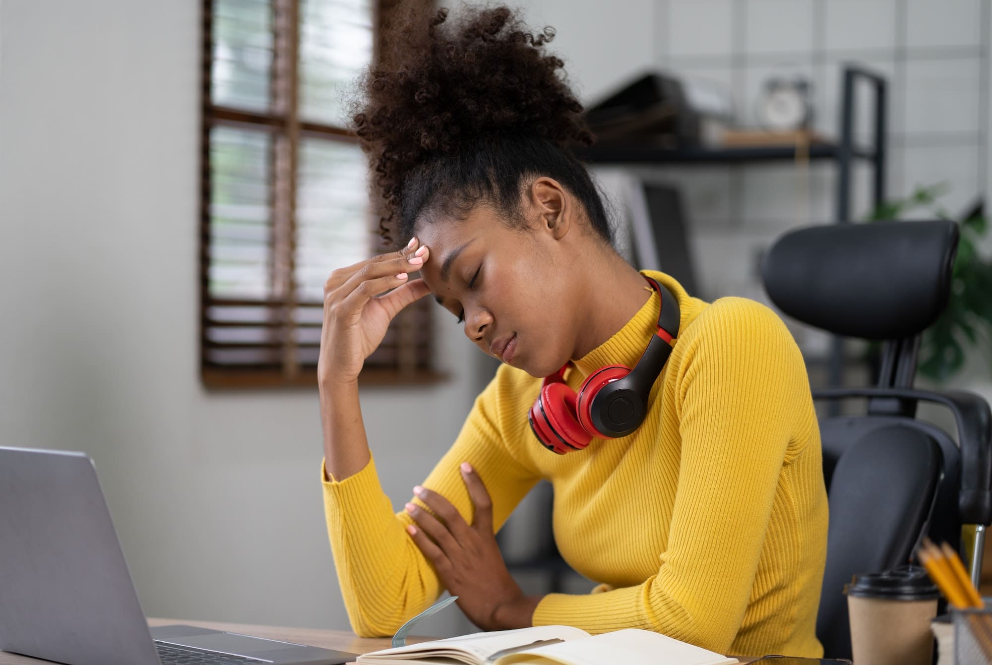 Young African American woman with afro hairstyle looks annoyed and stressed, sitting at the desk, us