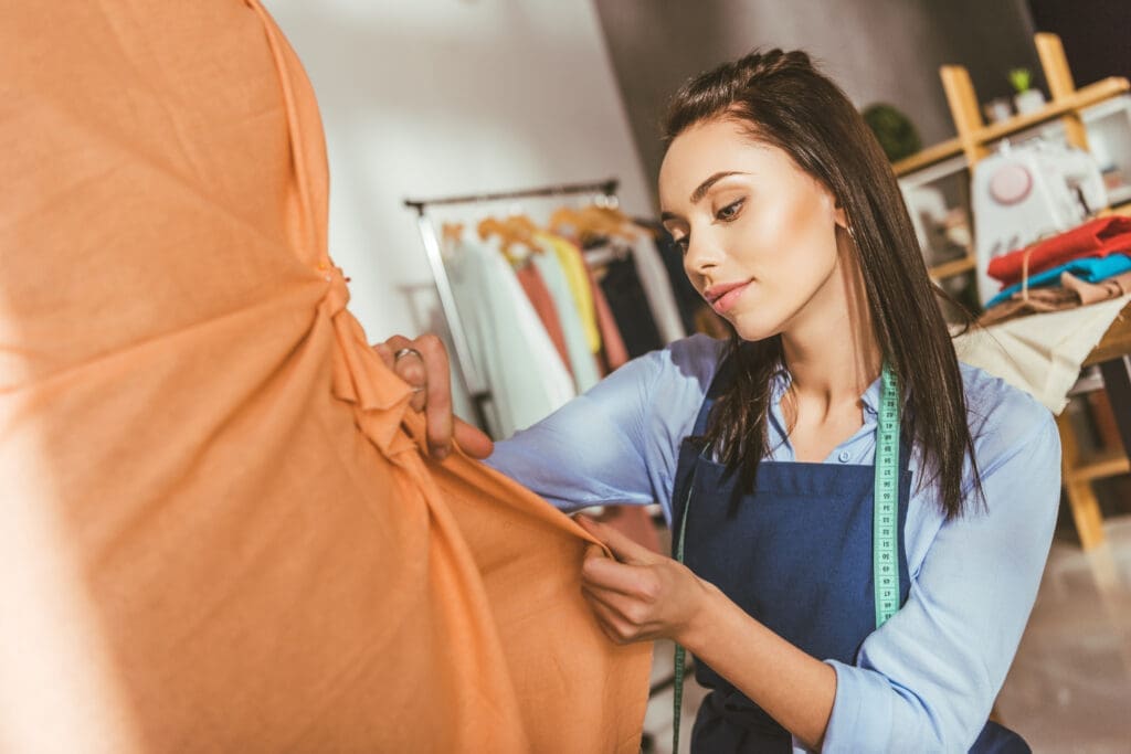 attractive tailor making dress on mannequin