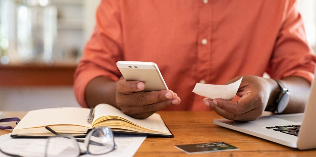 Man hands using smartphone and holding receipt