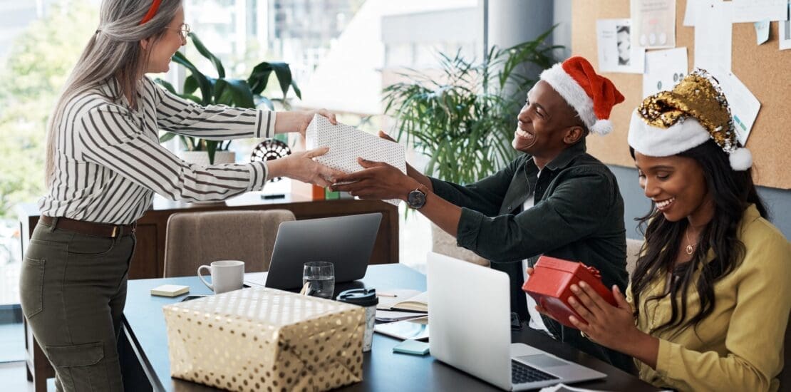 Shot of a group of businesspeople exchanging Christmas gifts in a modern office
