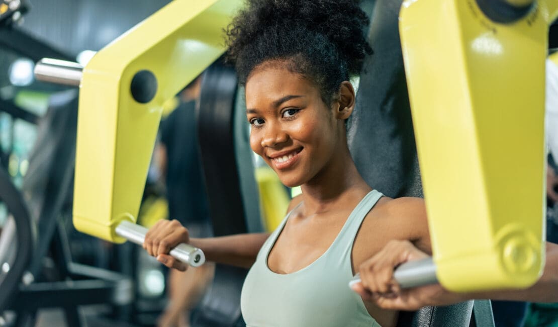 African sportswoman slow lift up weight machine or barbell in stadium.