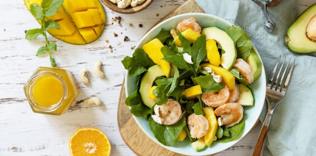 Vegetarian vegan healthy food. Salad with arugula, mango, avocado, shrimp, pecans.