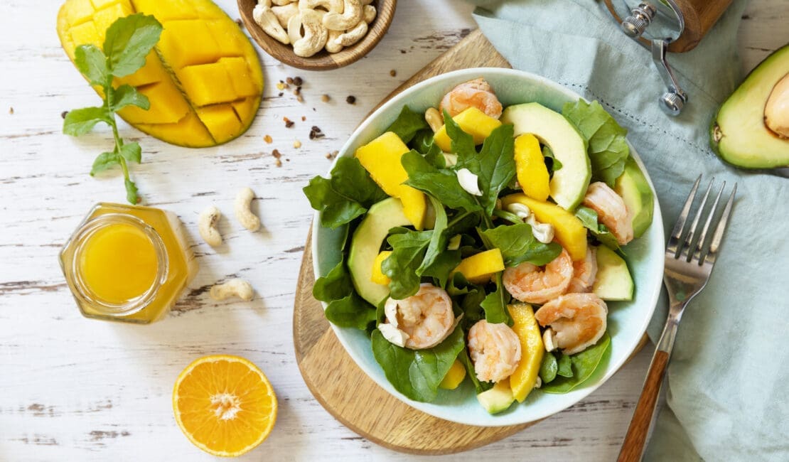 Vegetarian vegan healthy food. Salad with arugula, mango, avocado, shrimp, pecans.